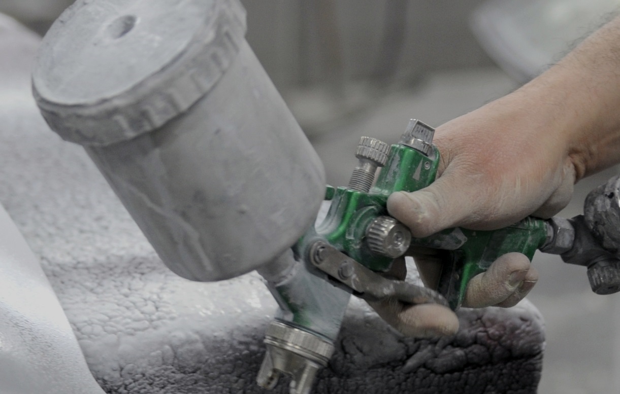 Aplicação de revestimento automóvel com pistola de pintura em ambiente industrial, ilustrando soluções técnicas testadas diretamente na linha de produção.
